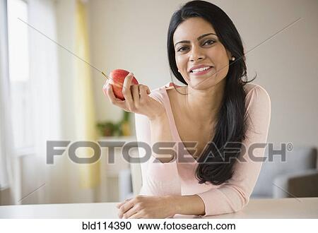 Stock Image - Indian woman eating fruit. Fotosearch