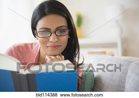 Stock Photo - Indian woman reading on sofa. Fotosearch