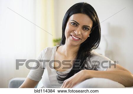 Picture - Indian woman smiling on sofa. Fotosearch
