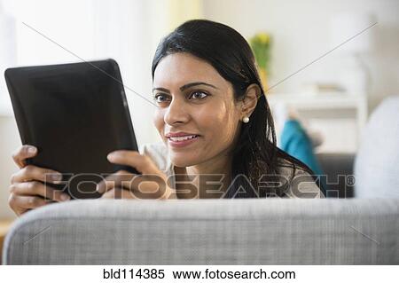 Indian woman using tablet computer on sofa View Large Photo Image Stock Photography - Indian woman using tablet computer on sofa. Fotosearch