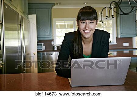 Mixed race businesswoman using laptop in kitchen View Large Photo Image Stock Image - Mixed race businesswoman using laptop in kitchen. Fotosearch