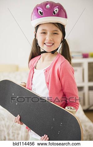Stock Photograph - Mixed race girl holding skateboard. Fotosearch