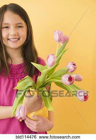 Stock Photograph - Mixed race girl holding vase of flowers. Fotosearch