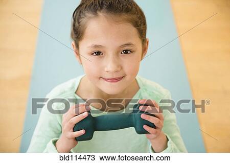Stock Image - Mixed race girl holding weight on yoga mat. Fotosearch