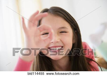 Stock Photography - Mixed race girl making O. K. sign with fingers. Fotosearch