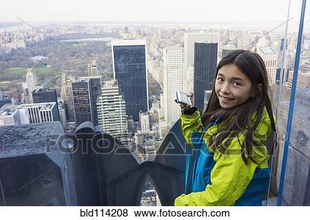 Stock Photo - Mixed race girl taking pictures from rooftop, New York City, New York, United States. Fotosearch