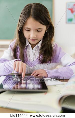 Picture - Mixed race girl using tablet computer in class. Fotosearch
