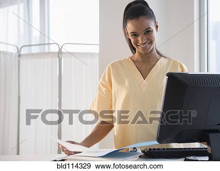 Stock Photo - Mixed race nurse using computer in hospital. Fotosearch