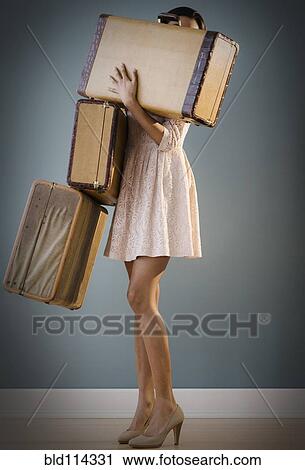 Stock Image - Mixed race woman carrying suitcases. Fotosearch