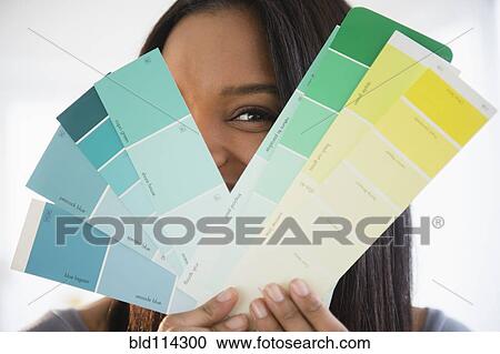 Stock Image - Mixed race woman holding paint swatches. Fotosearch