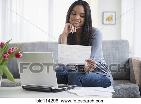 Mixed race woman paying bills with laptop View Large Photo Image Stock Photograph - Mixed race woman paying bills with laptop. Fotosearch