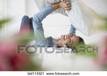 Mixed race woman playing with pillow View Large Photo Image Stock Image - Mixed race woman playing with pillow. Fotosearch
