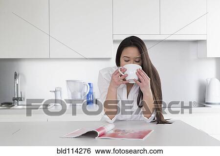 Mixed race woman reading magazine in kitchen View Large Photo Image Stock Photograph - Mixed race woman reading magazine in kitchen. Fotosearch