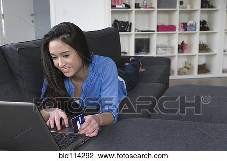 Stock Image - Mixed race woman shopping online on sofa. Fotosearch