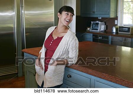 Mixed race woman smiling in kitchen View Large Photo Image Stock Photo - Mixed race woman smiling in kitchen. Fotosearch