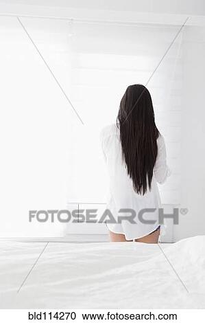 Stock Image - Mixed race woman standing in bedroom. Fotosearch