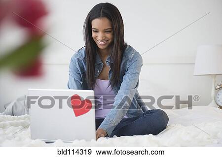 Mixed race woman using laptop on bed View Large Photo Image Stock Photo - Mixed race woman using laptop on bed. Fotosearch