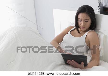 Mixed race woman using tablet computer in bed View Large Photo Image Stock Photo - Mixed race woman using tablet computer in bed. Fotosearch