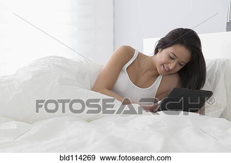 Mixed race woman using tablet computer in bed View Large Photo Image Stock Photo - Mixed race woman using tablet computer in bed. Fotosearch