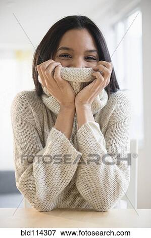 Stock Photo - Mixed race woman wrapped in sweater. Fotosearch