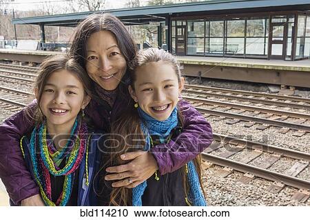 Stock Image - Mother and daughters smiling at train station. Fotosearch