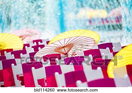 Stock Image - Parasols and silk scarves on chairs outdoors. Fotosearch