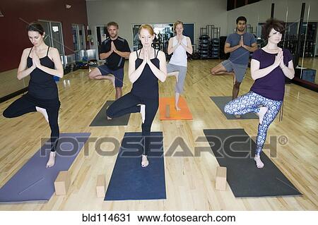 Stock Image - People practicing yoga in class. Fotosearch