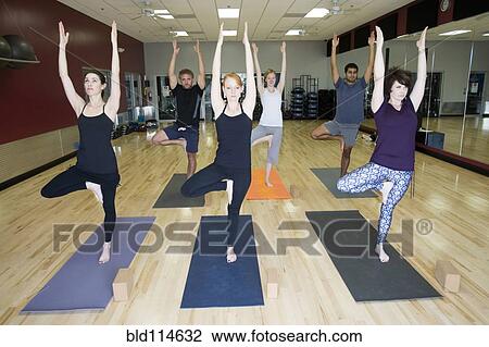 Stock Image - People practicing yoga in class. Fotosearch