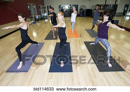 Stock Image - People practicing yoga in class. Fotosearch