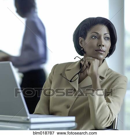 Stock Photo - African American businesswoman sitting at desk. Fotosearch