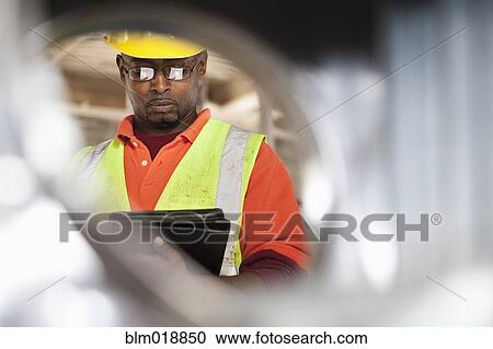 Stock Image - African American construction worker using digital tablet. Fotosearch