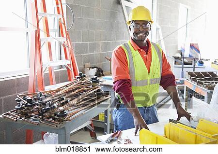 Stock Image - African American construction worker smiling at construction site. Fotosearch