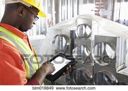 Stock Photo - African American construction worker using digital tablet. Fotosearch