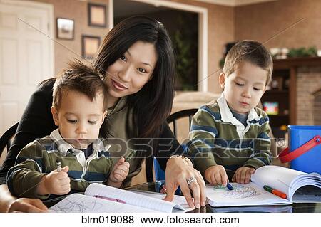 Stock Photo - Asian mother watching sons draw with crayons. Fotosearch