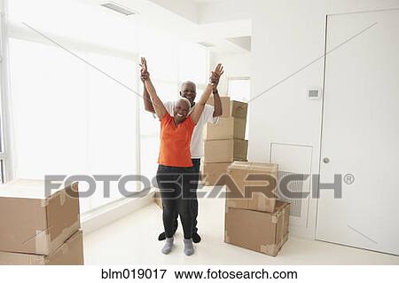 Stock Photo - Black couple cheering in new home. Fotosearch