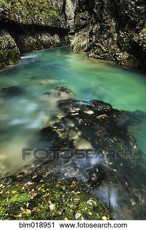 Stock Image - Blurred view of river rushing over rock formations. Fotosearch