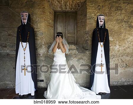 Stock Photo - Bride standing between priest statues at church. Fotosearch