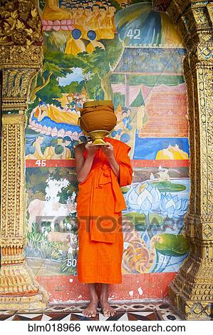 Buddhist monk carrying offering in temple, Luang Prabang, Luang Prabang, Laos View Large Photo Image Stock Photograph - Buddhist monk carrying offering in temple, Luang Prabang, Luang Prabang, Laos. Fotosearch