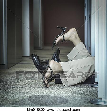 Stock Image - Business people's feet poking out office doorway. Fotosearch