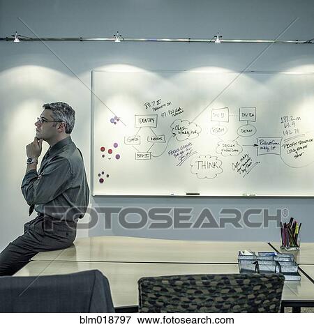 Stock Photo - Caucasian businessman sitting on desk. Fotosearch