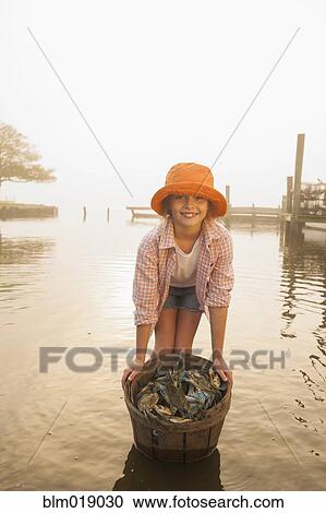 Stock Image - Caucasian girl holding basket of crabs. Fotosearch