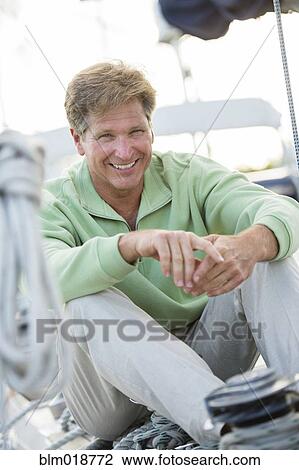 Caucasian man sitting on sailboat View Large Photo Image Stock Image - Caucasian man sitting on sailboat. Fotosearch