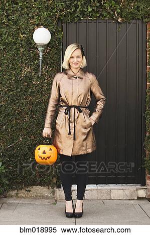 Stock Photography - Caucasian woman carrying jack o' lantern bucket. Fotosearch