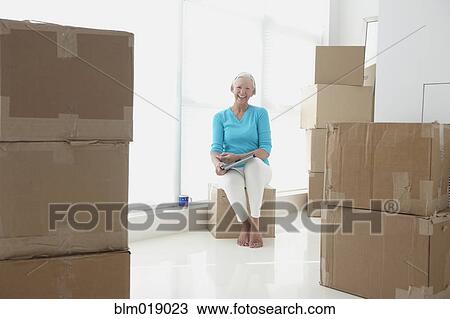 Stock Image - Caucasian woman reading in new home. Fotosearch