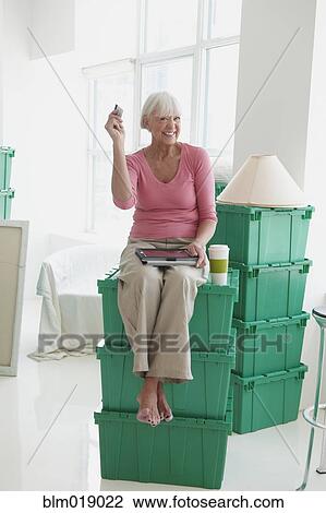 Stock Image - Caucasian woman using digital tablet in new home. Fotosearch