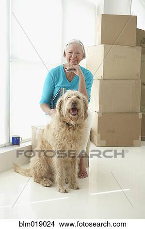 Picture - Caucasian woman with dog in new home. Fotosearch