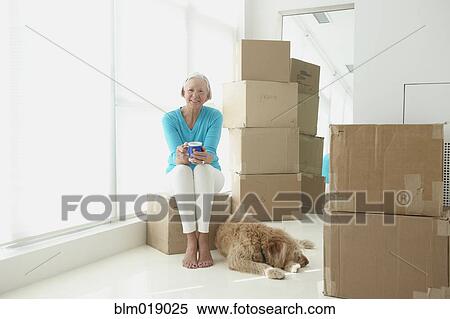 Stock Photography - Caucasian woman with dog in new home. Fotosearch