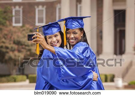 Stock Image - College graduates taking pictures together. Fotosearch