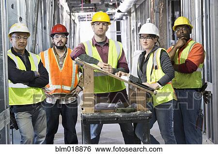 Stock Photograph - Construction workers standing at construction site. Fotosearch