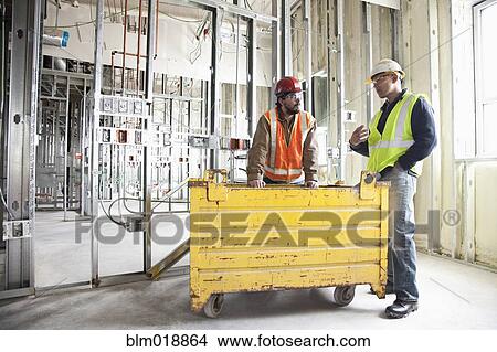 Picture - Construction workers talking at construction site. Fotosearch